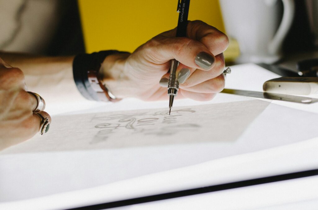 How to Stay Creative as a Graphic Designer person lettering on tracing paper using mechanical pencil